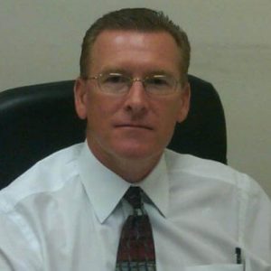 Businessman in white shirt and tie sitting in office chair, professional portrait.