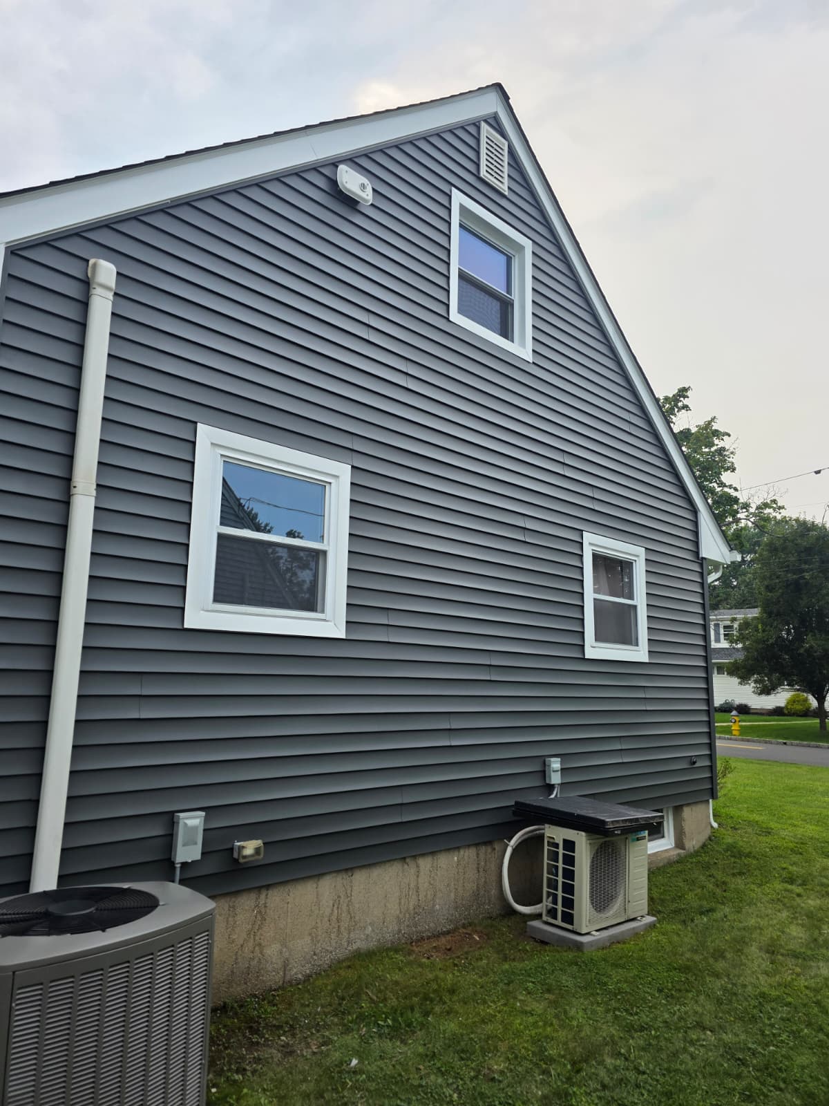 New gray vinyl siding and white-trimmed replacement windows installed by Star Windows Doors Siding on a Garfield, NJ home